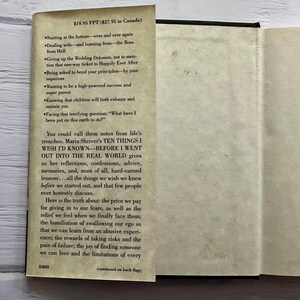 May include: An open book with text on the left page and a blank right page. The text includes the title "TEN THINGS I WISH I'D KNOWN" and a list of topics. The book is on a light-colored wooden surface.