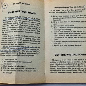 May include: Open book pages with text on self-confidence and goal setting. The text includes questions to ask about goals and steps to achieve them. The pages are aged with a yellowed tone.