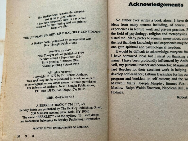 May include: Open book pages with text. The left page lists printing history, copyright information, and the ISBN of "The Ultimate Secrets of Total Self-Confidence" by Dr. Robert Anthony. The right page contains acknowledgements.