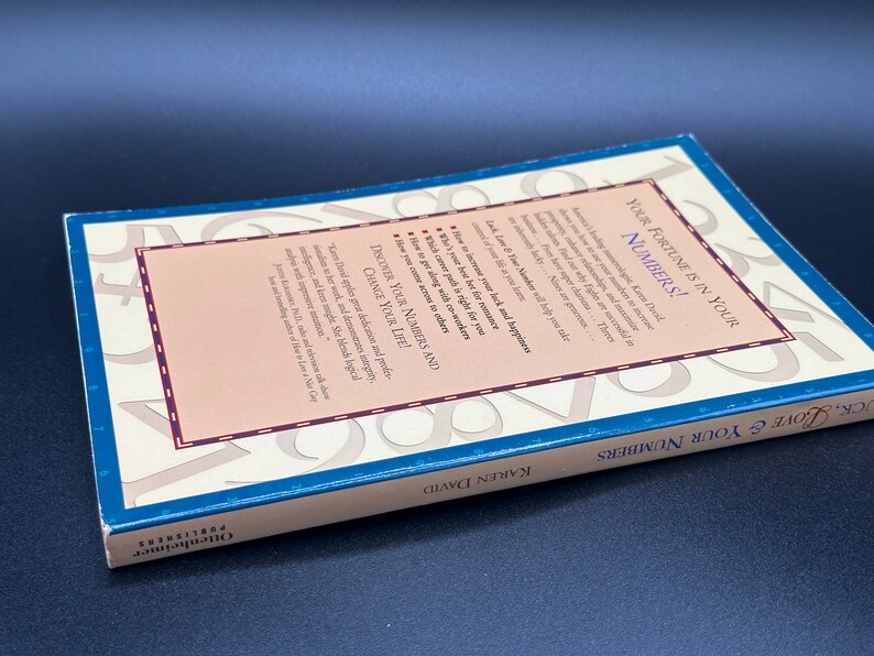 May include: A blue book titled "Your Fortune is in Your Numbers!" by Karen David. The back cover features a design of numbers and the text "Discover Your Numbers and Change Your Life!"