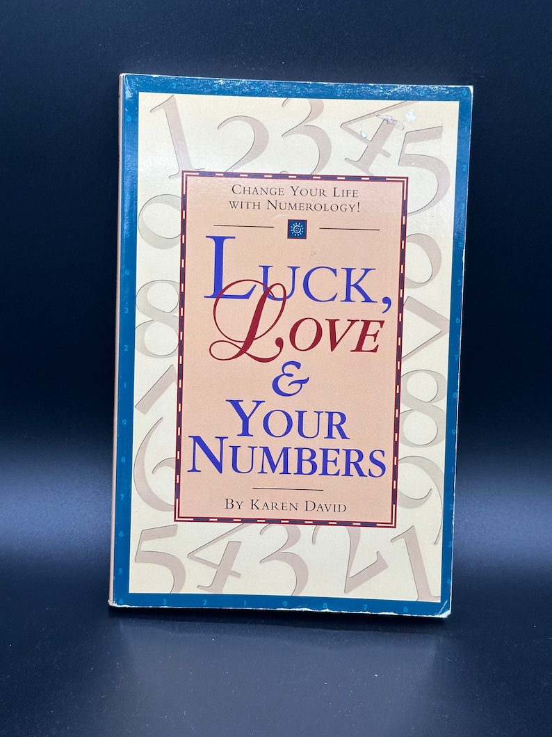 May include: A book titled "Luck, Love & Your Numbers" by Karen David. The cover features a background of numbers and the title in a red, white, and blue colour scheme. The book is about using numerology to change your life.