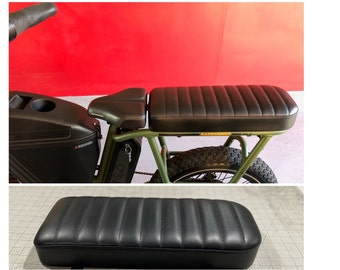 Puede incluir: Asiento de motocicleta de cuero negro con un diseño acanalado. El asiento está unido a una bicicleta eléctrica verde y negra con una caja de carga negra.
