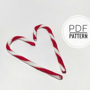 May include: Two crocheted candy canes with red and white stripes, arranged on a white background. The text "PDF PATTERN" is in a white circle in the upper right corner. These decorative candy canes are perfect for holiday crafting.