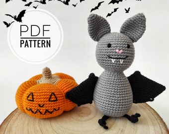 May include: Crochet pattern PDF for a gray bat and an orange pumpkin. The bat has black wings and a pink nose. The pumpkin has a jack-o'-lantern face.