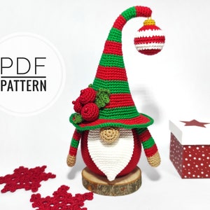 Peut inclure: Patron de crochet pour un gnome de Noël avec un chapeau rayé rouge et vert, une barbe blanche et une boule rouge et blanche. Le gnome est debout sur une base en bois. Le patron est disponible en téléchargement PDF.