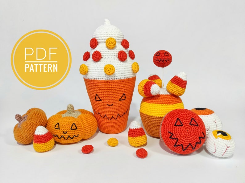 May include: A set of crocheted Halloween decorations, including a pumpkin-shaped ice cream cone, a candy corn-themed pumpkin, a candy corn, and a pumpkin-shaped ball. The decorations are all orange, yellow, and white.
