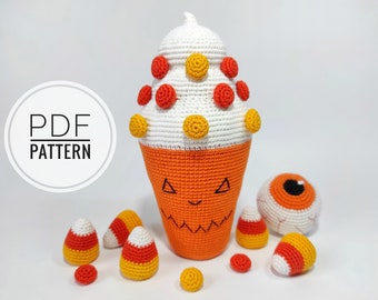 May include: Crochet pattern for a Halloween-themed candy corn ice cream cone with a jack-o'-lantern face, along with a crocheted eyeball and candy corn pieces. The pattern is available as a PDF download.