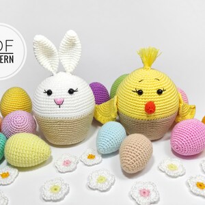 May include: Crocheted Easter bunny and chick amigurumi toys with a white background. The bunny is white with a brown bottom and the chick is yellow with a brown bottom. There are also several crocheted eggs in various colors.