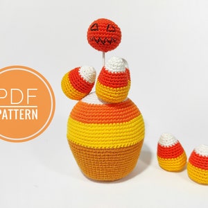 May include: Crochet pattern for a Halloween candy corn amigurumi. The pattern includes instructions for making a pumpkin head, a large candy corn body, and three smaller candy corn pieces. The pattern is available as a PDF download.