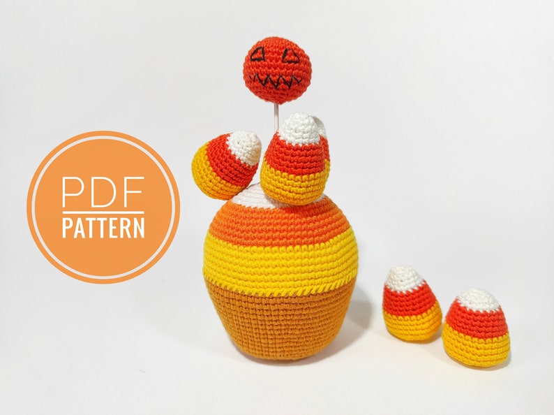 May include: Crochet pattern for a Halloween candy corn amigurumi. The pattern includes instructions for making a pumpkin head, a large candy corn body, and three smaller candy corn pieces. The pattern is available as a PDF download.