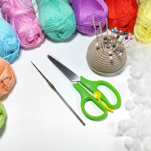 Puede incluir: Una colecci&oacute;n de ovillos de lana de colores, un alfiletero de ganchillo con alfileres, unas tijeras verdes, un ganchillo y relleno blanco.