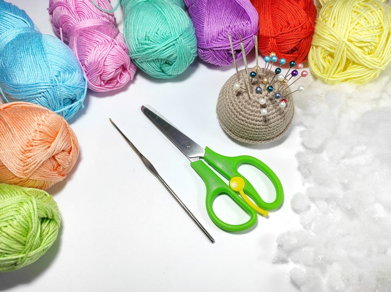 Puede incluir: Una colecci&oacute;n de ovillos de lana de colores, un alfiletero de ganchillo con alfileres, unas tijeras verdes, un ganchillo y relleno blanco.