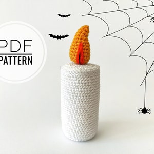 May include: A white crocheted candle with an orange crocheted flame on top. The candle is surrounded by black spiderwebs and spiders.