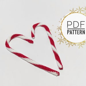 May include: Two handmade crochet candy canes with red and white stripes, arranged on a white surface. The image includes a circular graphic with the text "PDF PATTERN".