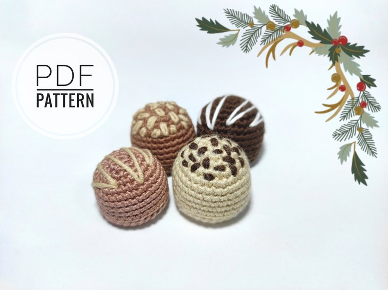 May include: Four crocheted chocolate truffles in different colors and designs. The truffles are brown, beige, and pink. The truffles have different designs, including white stripes, brown sprinkles, and brown swirls.
