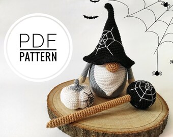 Può includere: Uno gnomo di Halloween all'uncinetto con cappello nero e disegno a ragnatela, una zucca e un martello. Lo gnomo ha un corpo grigio, barba bianca e naso beige. L'immagine include il testo "PDF PATTERN".