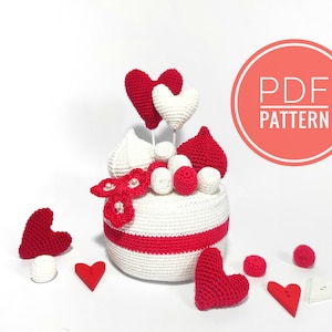 May include: Crochet pattern for a white cake with red hearts and white and red frosting. The pattern is available as a PDF download.