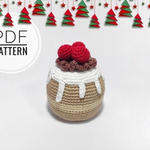 May include: Crochet pattern for a Christmas pudding ornament. The ornament is brown and beige with white icing and red cherries on top. The pattern is available as a PDF download.