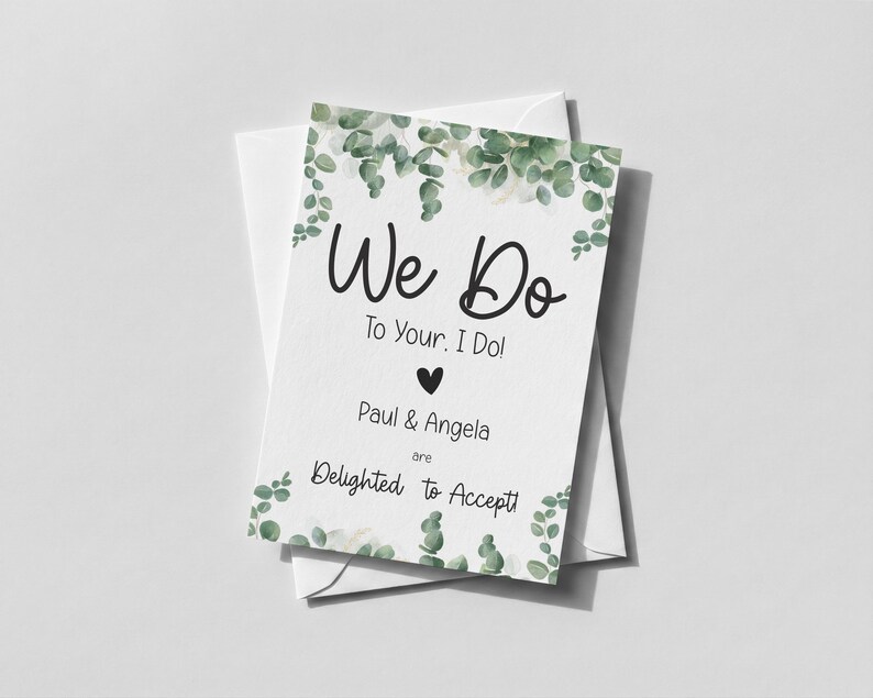 Puede incluir: Una tarjeta de respuesta de boda rectangular blanca con ilustraciones de hojas de eucalipto verdes en la parte superior e inferior. El texto dice: We Do To Your, I Do! Paul & Angela are Delighted to Accept! Un peque&ntilde;o coraz&oacute;n negro est&aacute; centrado.
