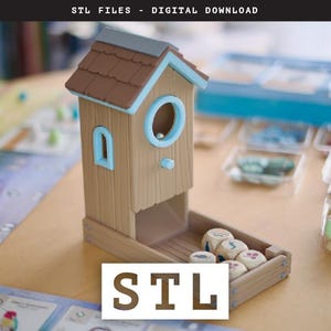 Op de afbeelding: Een houten dobbelsteentoren in de vorm van een vogelhuisje met een blauw dak en een blauw raam. De toren is aan één kant open om een ​​lade voor dobbelstenen te onthullen. De toren staat op een houten tafel met dobbelstenen erin. De tekst "STL" is in grote letters onder de toren gedrukt.