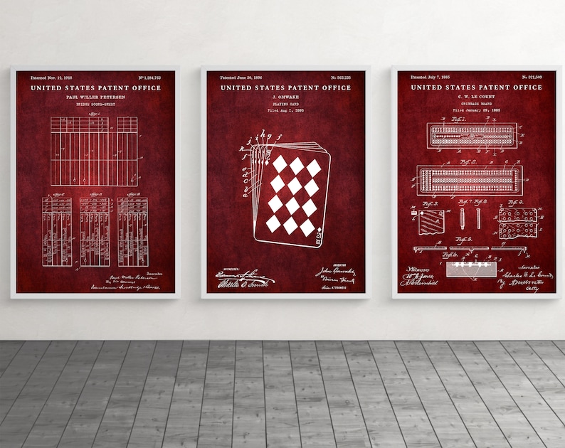 May include: Three framed patent prints with white diagrams on a deep red background. The prints feature designs for playing cards and a bridge score-sheet. The frames are white, and the prints are displayed on a gray floor.