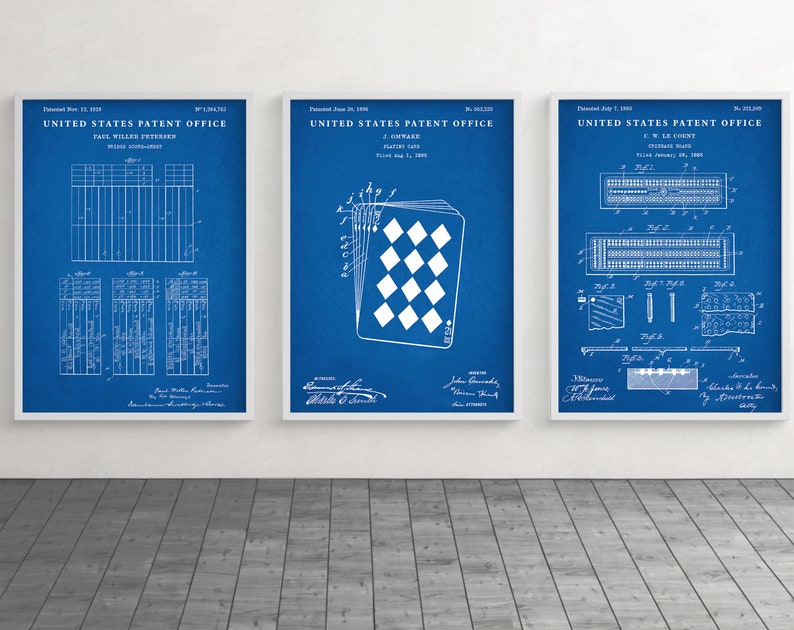 May include: Three framed patent prints with white frames. The prints feature white technical drawings on a blue background. The prints include text from the United States Patent Office. One print shows a playing card design.