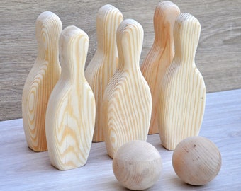 May include: A set of ten wooden bowling pins and a wooden bowling ball. The pins are all natural wood color and have a smooth finish. The ball is also natural wood color and has a slightly rougher finish.