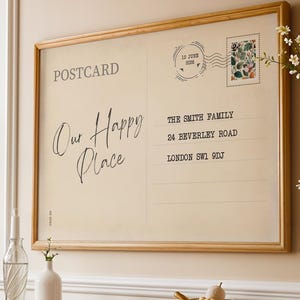 May include: A rectangular framed wall art piece designed as a vintage postcard with the text POSTCARD, Our Happy Place, and an address for The Smith Family, 24 Beverley Road, London SW1 9DJ, featuring a postage stamp and a circular postmark.