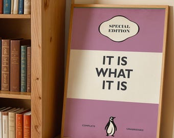 May include: A framed rectangular print featuring a purple and cream color scheme with the text "SPECIAL EDITION" at the top and "IT IS WHAT IT IS" in the center. A small penguin illustration is at the bottom with the words "COMPLETE" and "UNABRIDGED".