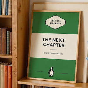 Pode incluir: Uma impressão retangular emoldurada com fundo verde e creme apresentando o texto "SPECIAL EDITION" no topo, "THE NEXT CHAPTER" no centro e "IS READY TO BE WRITTEN" abaixo, com uma pequena ilustração de pinguim na parte inferior.