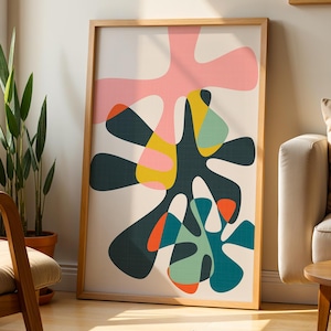 May include: A rectangular framed wall art piece featuring an abstract composition of organic, fluid shapes in shades of dark green, light pink, yellow, teal, and orange against a cream-colored background, enclosed in a light wood frame.