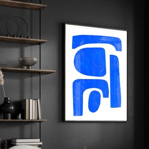 May include: A framed wall art piece featuring a white background with bold, abstract blue shapes. The artwork consists of a horizontal bar at the top, a large rounded square, and a vertical rectangular form with a smaller circular shape below.