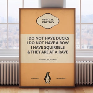 May include: A rectangular framed poster with an orange and cream background. The text reads: SPECIAL EDITION, I DO NOT HAVE DUCKS, I DO NOT HAVE A ROW, I HAVE SQUIRRELS, & THEY ARE AT A RAVE, AN AUTOBIOGRAPHY, COMPLETE, UNABRIDGED, with a penguin icon.