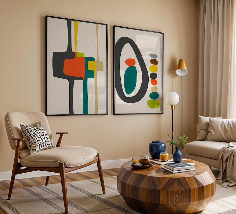 May include: Two framed wall art prints featuring abstract geometric shapes in charcoal, orange, teal, and yellow on a light background. The left print displays vertical lines and block forms, while the right print shows a large oval with stacked circles.