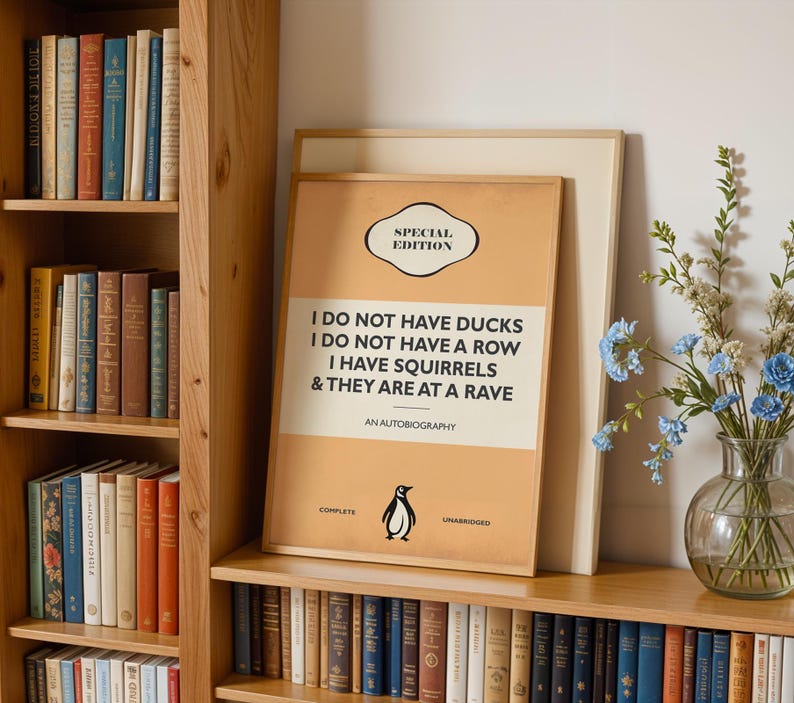 May include: A framed rectangular poster with a tan background featuring the text SPECIAL EDITION, I DO NOT HAVE DUCKS, I DO NOT HAVE A ROW, I HAVE SQUIRRELS & THEY ARE AT A RAVE, AN AUTOBIOGRAPHY, COMPLETE, and UNABRIDGED with a small penguin icon.