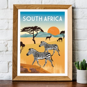 May include: A vintage travel poster featuring a sunset over a savanna landscape with zebras, antelopes, and a tree. The poster is framed in wood and has the text "SOUTH AFRICA" at the top.
