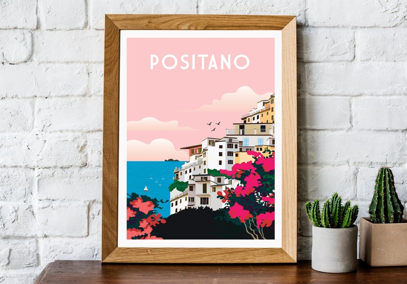 May include: A framed poster with a pink background and a colorful illustration of the town of Positano, Italy. The text "POSITANO" is printed in white at the top of the poster.