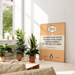 May include: A rectangular poster with a tan and cream background featuring the text "SPECIAL EDITION", "I DO NOT HAVE DUCKS I DO NOT HAVE A ROW I HAVE SQUIRRELS & THEY ARE AT A RAVE", "AN AUTOBIOGRAPHY", "COMPLETE", "UNABRIDGED", and a penguin icon.