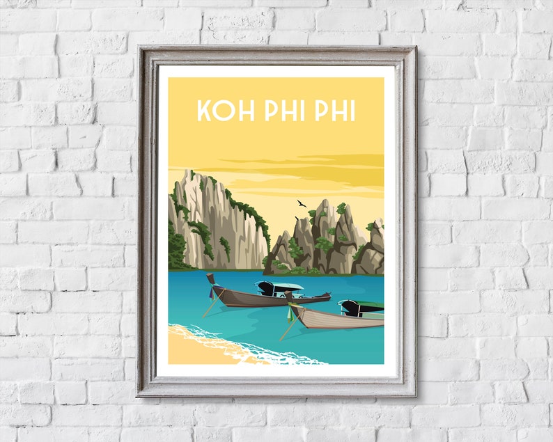 May include: Framed art print featuring a scenic illustration of Koh Phi Phi, Thailand. The artwork depicts a yellow sky, turquoise water, limestone cliffs, traditional boats, and the text "KOH PHI PHI" in a yellow font.