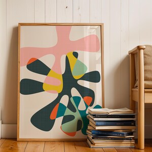 May include: A framed wall art print featuring an abstract composition of organic, amoeba-like shapes in shades of pink, dark green, yellow, teal, and orange against a cream background, enclosed in a light-toned wooden frame.