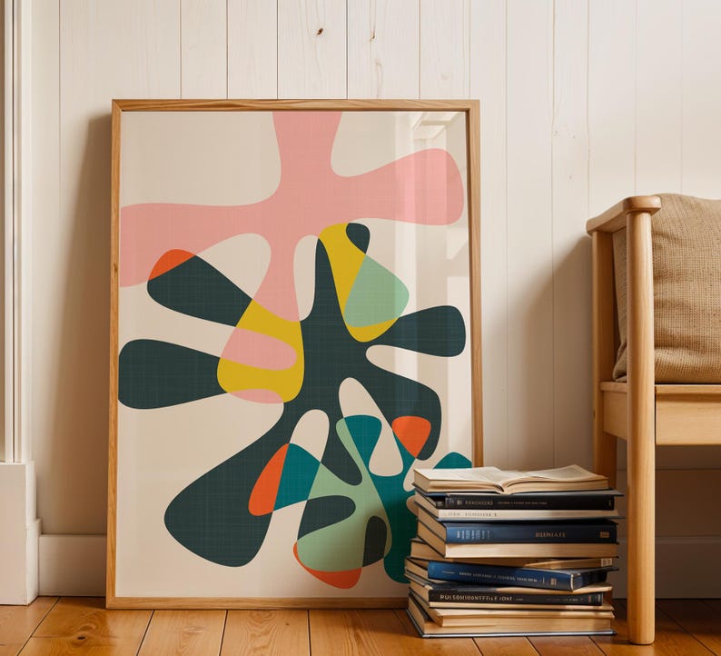 May include: A framed wall art print featuring an abstract composition of organic, amoeba-like shapes in shades of pink, dark green, yellow, teal, and orange against a cream background, enclosed in a light-toned wooden frame.