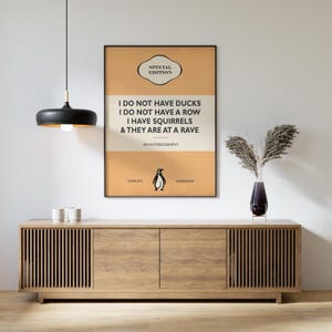 May include: A rectangular wall poster with a tan and cream background featuring the text: SPECIAL EDITION, I DO NOT HAVE DUCKS, I DO NOT HAVE A ROW, I HAVE SQUIRRELS & THEY ARE AT A RAVE, AN AUTOBIOGRAPHY, COMPLETE, UNABRIDGED, and a small penguin icon.