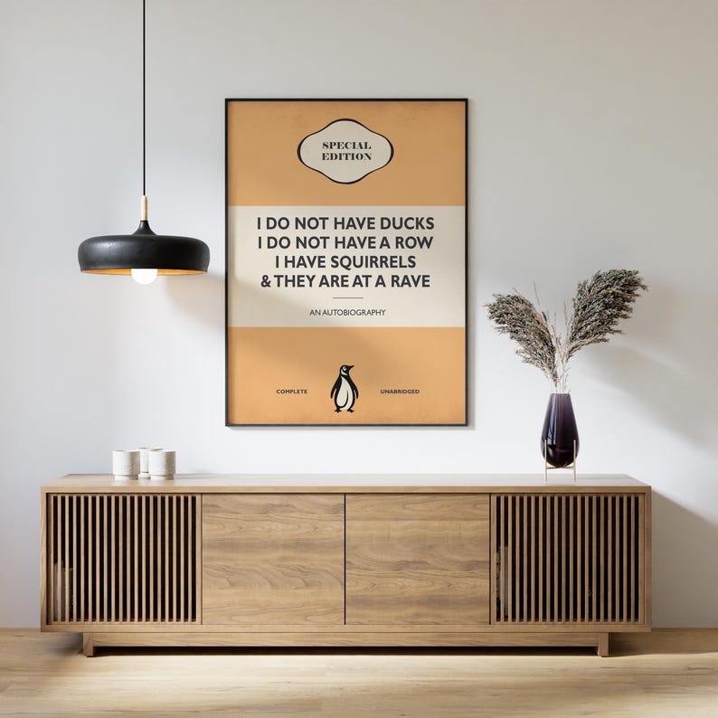 May include: A rectangular wall poster with a tan and cream background featuring the text: SPECIAL EDITION, I DO NOT HAVE DUCKS, I DO NOT HAVE A ROW, I HAVE SQUIRRELS & THEY ARE AT A RAVE, AN AUTOBIOGRAPHY, COMPLETE, UNABRIDGED, and a small penguin icon.