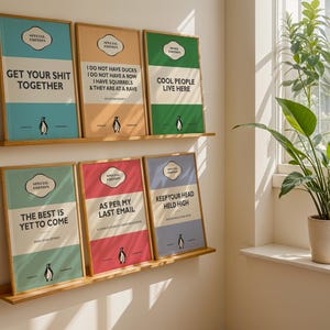 May include: Six framed rectangular wall art prints arranged on two wooden shelves. Each print features a colorful background, a penguin illustration, and text including phrases like GET YOUR SHIT TOGETHER, AS PER MY LAST EMAIL, and COOL PEOPLE LIVE HERE.
