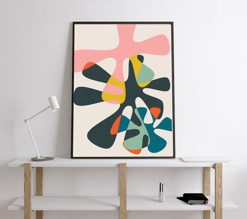May include: A framed vertical wall art print featuring an abstract composition of overlapping organic shapes in shades of dark charcoal, soft pink, mustard yellow, teal, light green, and bright orange against a light cream background.