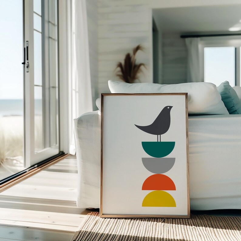 May include: A framed vertical art print featuring a dark gray bird perched atop a vertical stack of four semi-circles. The semi-circles are colored in teal, light gray, orange, and yellow, arranged in a column against a plain white background.