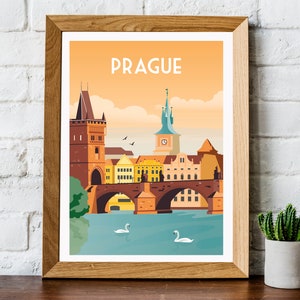 May include: A framed illustration of the Charles Bridge in Prague, Czech Republic. The illustration features a colorful cityscape with a bridge, buildings, and swans in the water. The text "PRAGUE" is at the top of the illustration.