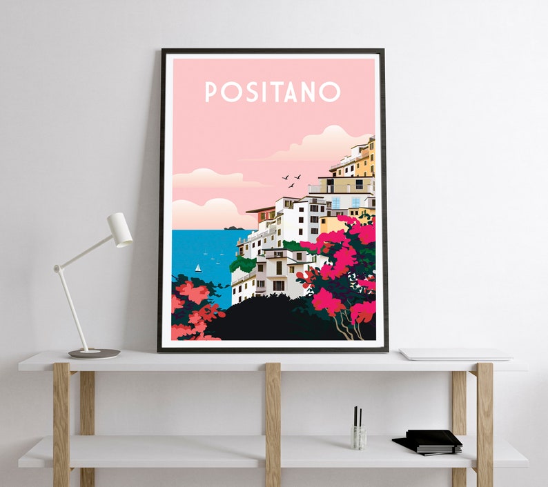 May include: A colorful illustration of Positano, Italy, with white buildings on a cliffside overlooking a blue sea. The sky is pink with clouds and there are pink flowers in the foreground.