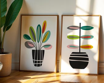 May include: Two framed rectangular wall art prints featuring stylized potted plants. The left print shows a plant with multi-colored oval leaves in a grid-patterned pot. The right print displays a plant with symmetrical leaves in a striped pot.