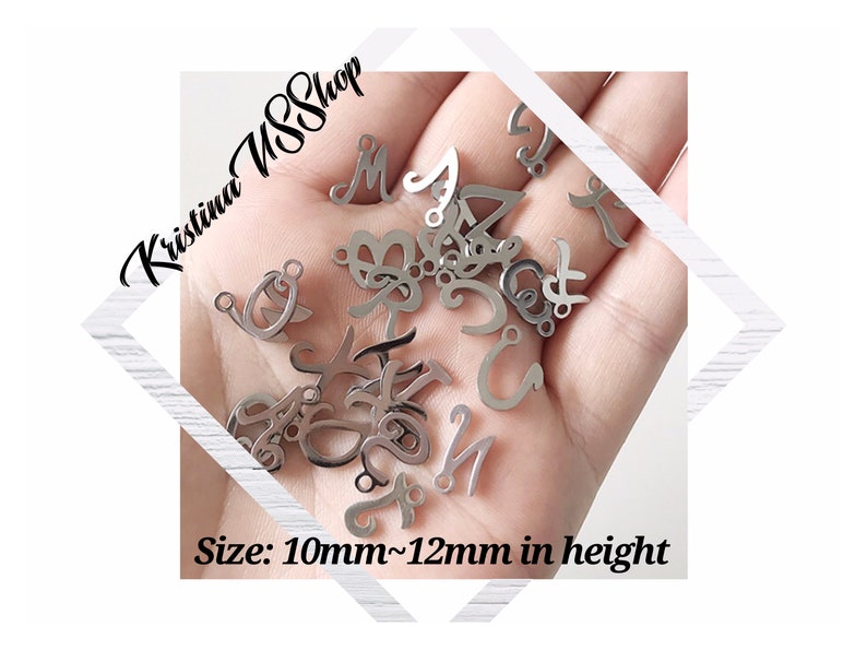 May include: A close-up of a hand holding a variety of silver metal letter charms. The charms are approximately 10mm to 12mm in height. The text "Kristina SSShop" is visible in the background.